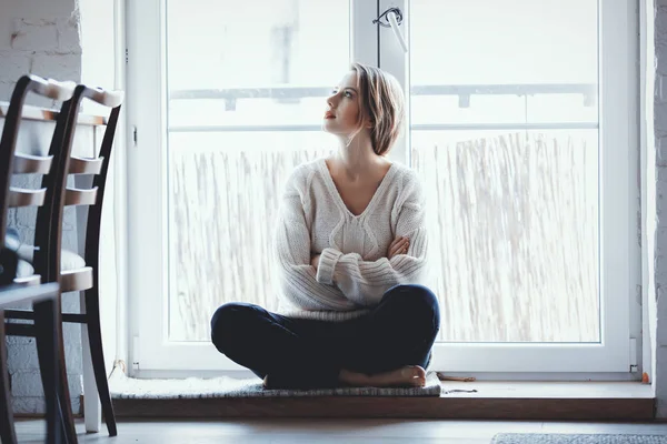 Chica vestida con un suéter está sentado en el umbral — Foto de Stock
