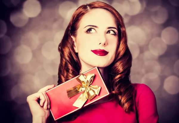 ギフト用の箱と赤いドレスのスタイルの赤毛の女性 — ストック写真