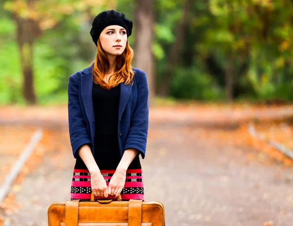 样式红头发的女孩在贝雷帽, 夹克和裙子与手提箱 — 图库照片
