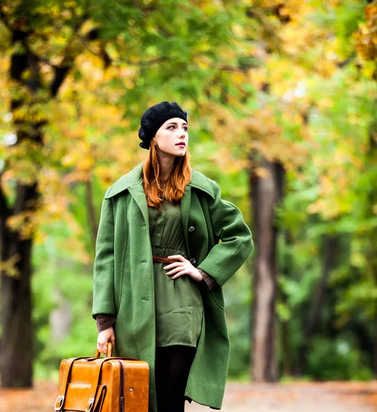 Chica pelirroja de estilo en boina y abrigo con maleta — Foto de Stock