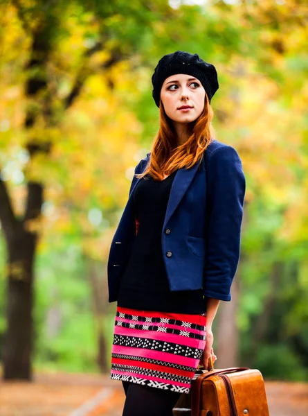Stijl roodharige meisje in baret, jas en rok met koffer — Stockfoto