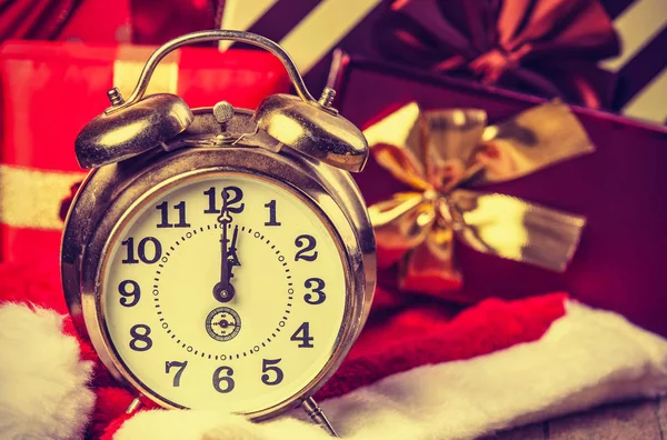 Alarm clock on Santa Claus hat and gifts — Stock Photo, Image