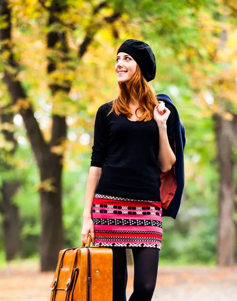 Stile rossa ragazza in berretto, giacca e gonna con valigia — Foto Stock