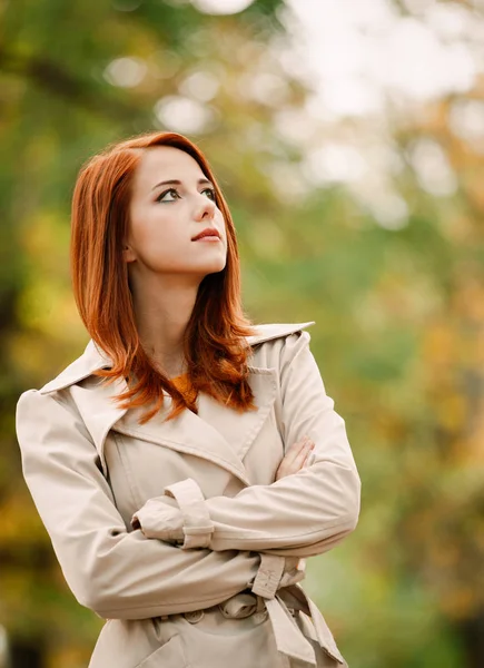 Mode rödhårig kvinna i mantel i park — Stockfoto