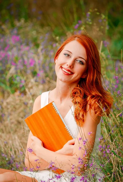 Rödhårig tjej i vit klänning med notebook — Stockfoto