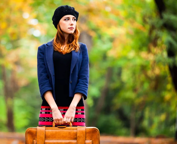 Stile rossa ragazza in berretto, giacca e gonna con valigia — Foto Stock