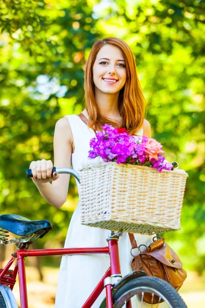 Rödhårig tjej i vit klänning med röda cykel — Stockfoto