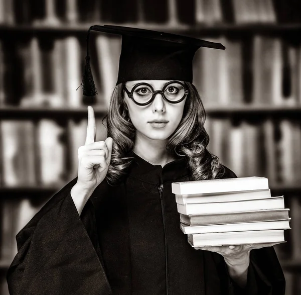 Abschlussschülerin im akademischen Kleid mit Büchern — Stockfoto