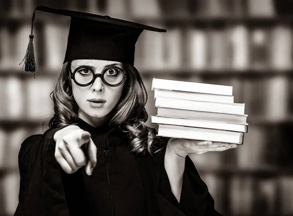 Abschlussschülerin im akademischen Kleid mit Büchern — Stockfoto