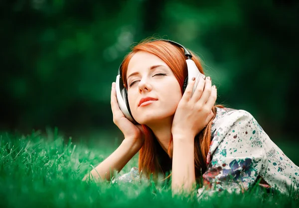 Mooie Jonge Roodharige Vrouw Hoofdtelefoons Gazon Een Park Zijaanzicht — Stockfoto