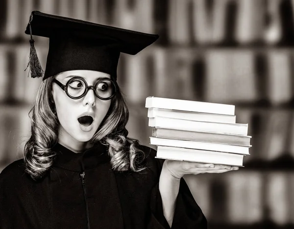Graduating student girl in an academic gown with books — Stock Photo, Image