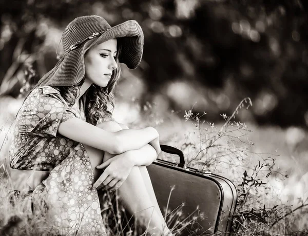 Mädchen mit Koffer sitzt im Herbstgras — Stockfoto