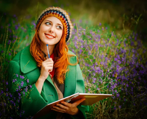 Dziewczyna trzyma notebook i siedzi w trawie gren — Zdjęcie stockowe