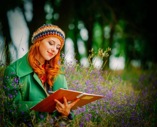 Dívka drží notebook a sedí u gren trávy — Stock fotografie