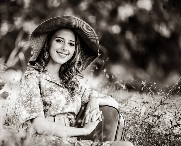Девушка с чемоданом сидит на осенней траве — стоковое фото