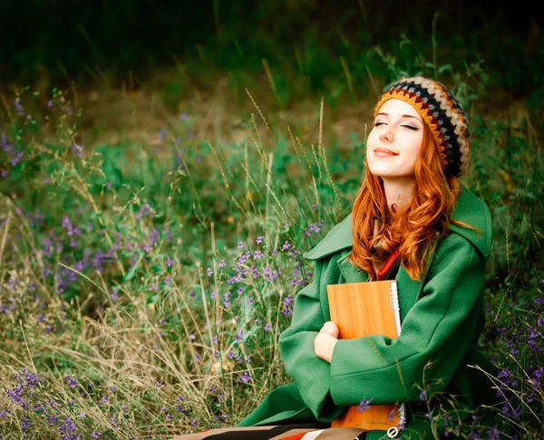 Girl holding notebook and sitting at gren grass — Stock Photo, Image