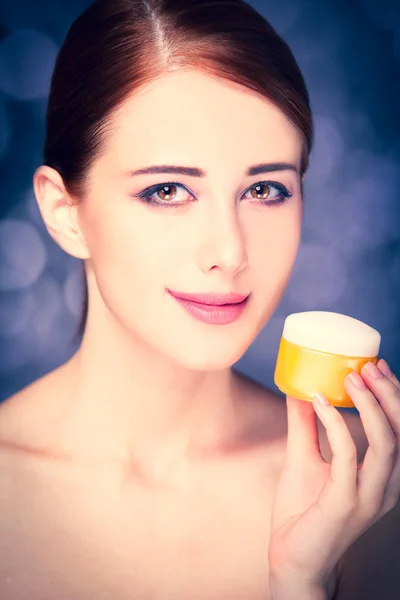 Young redhead woman with cosmetic cream — Stock Photo, Image