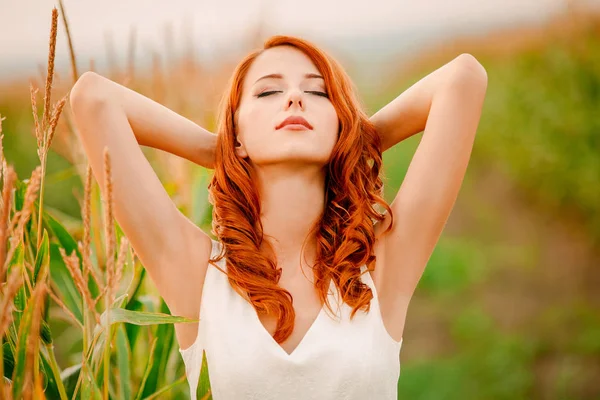 Chica está de pie en un campo de mazorcas de maíz — Foto de Stock