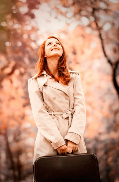 Девушка с чемоданом в парке осеннего сезона — стоковое фото