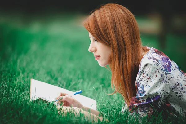 Vöröshajú lány a zöld gyepen notebook — Stock Fotó