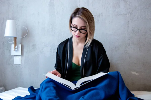 Mulher branca sentada na cama com livro — Fotografia de Stock