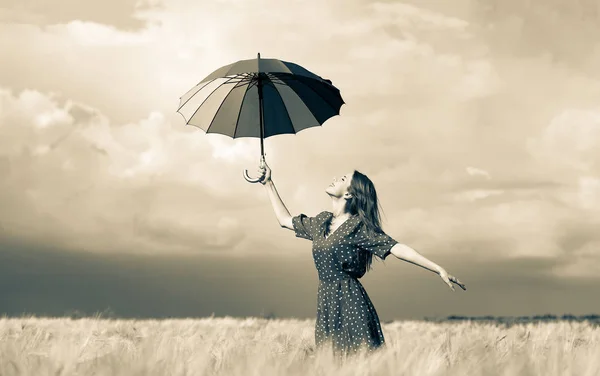 Menina está de pé em um campo de trigo com guarda-chuva — Fotografia de Stock