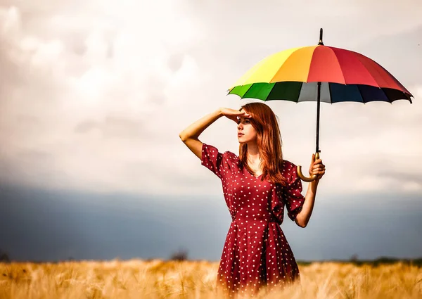 Chica está de pie en un campo de trigo con paraguas — Foto de Stock