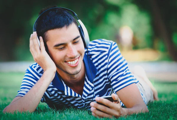 Mann mit Kopfhörer legt sich auf grünen Rasen — Stockfoto