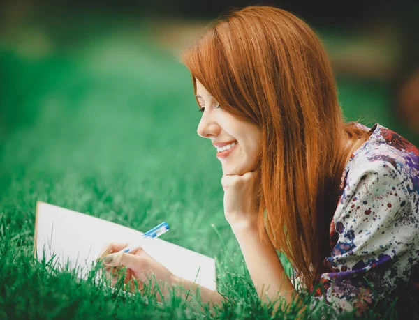 Zrzka dívka s notebookem na zeleném trávníku — Stock fotografie
