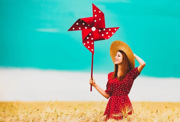 Девушка стоит на пшеничном поле с вертушкой — стоковое фото