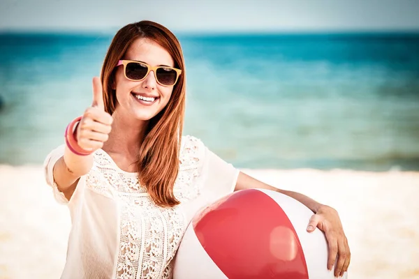 Menina em óculos de sol com praia bola mostrar OK — Fotografia de Stock