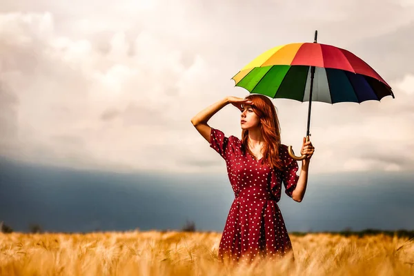 Menina está de pé em um campo de trigo com guarda-chuva — Fotografia de Stock