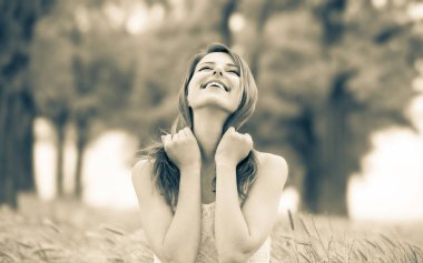 Bir parkta çim üzerinde oturan güzel kız.