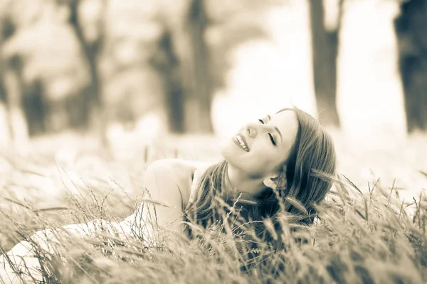 Menina bonita sentada na grama em um parque . — Fotografia de Stock