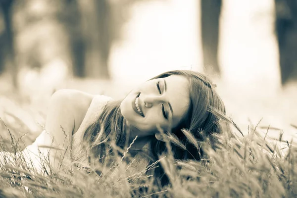 Piękna dziewczyna siedzi na trawie w parku. — Zdjęcie stockowe