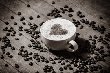 Bir fincan kahve ve kalp şekli sembolü içindeki ahşap masa. Görünümünün üzerinde. Görüntü siyah beyaz renk tarzı.