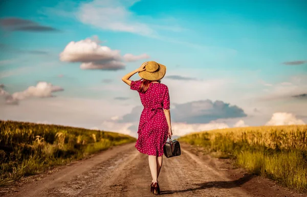 Девушка с чемоданом просыпается на сельской дороге — стоковое фото