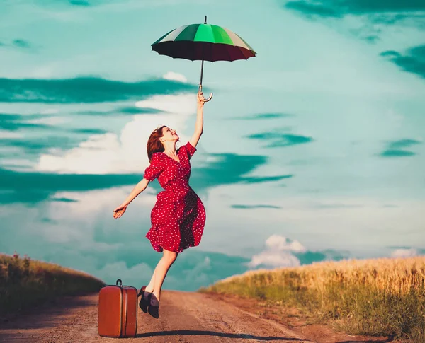 Fille avec parapluie et valise à la campagne — Photo