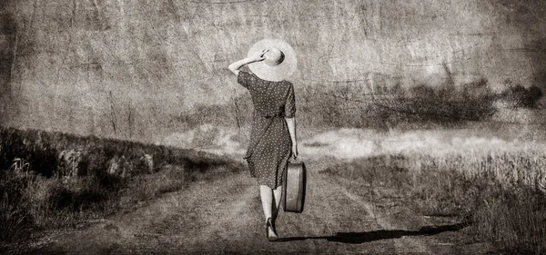 Flicka med suicase på vägen nära vetefält — Stockfoto