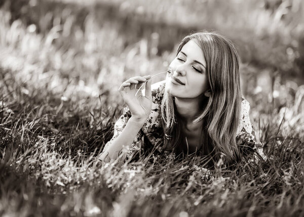 Beautiful girl lying down on grass in a park. Image in black and white color style