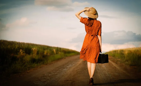 Dziewczyna z walizką, budząc się na wiejskiej drodze — Zdjęcie stockowe