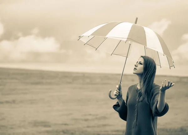 Девушка в свитере с зонтиком на пшеничном поле — стоковое фото