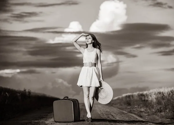 田舎道でスーツケースを白いドレスで美しい赤毛の女の子 黒と白のカラー スタイルのイメージ — ストック写真