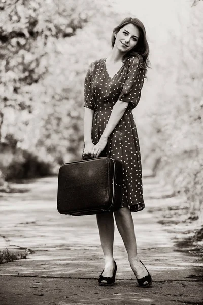Dziewczyna z walizką podróży pobyt na wiejskiej drodze — Zdjęcie stockowe