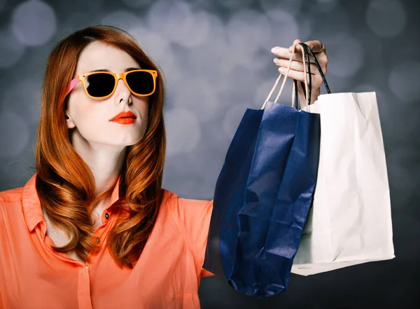 Стильная девушка с сумками для покупок на сером фоне — стоковое фото