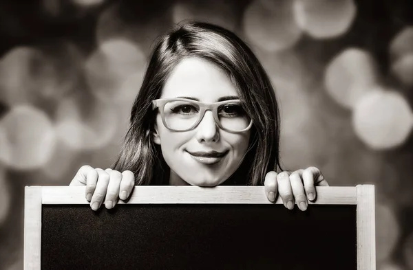 Jeune femme avec tableau noir et lunettes — Photo