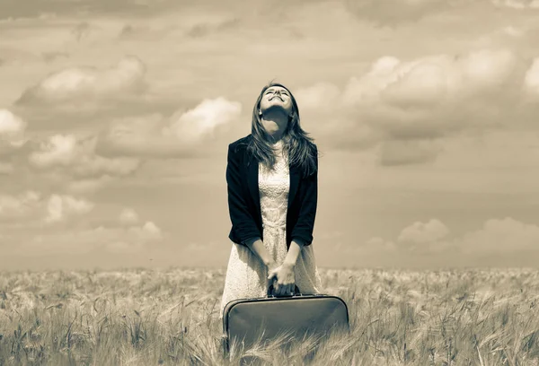 Девушка с чемоданом на пшеничном поле Стоковое Изображение
