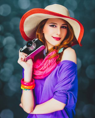 Kamera ve bokeh arka plan üzerinde şapkalı Kızıl saçlı kız