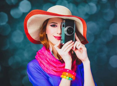 Kamera ve bokeh arka plan üzerinde şapkalı Kızıl saçlı kız