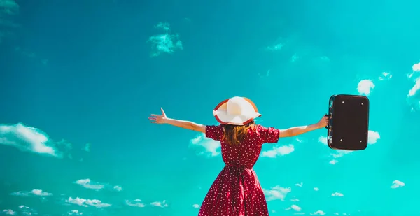 Girl with open arms holds a suitcase on blue sky — Stock Photo, Image